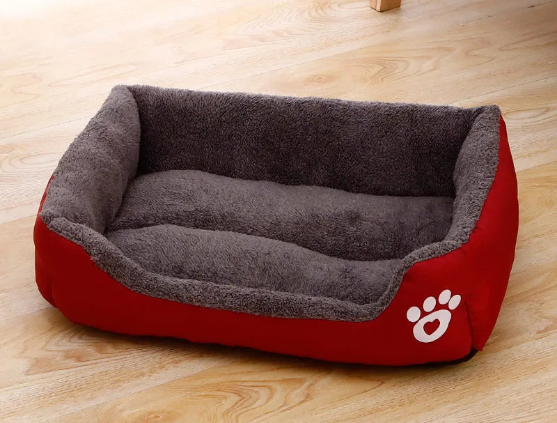 Panier matelassé rouge vide, posé sur un parquet, coussin gris à l'intérieur
