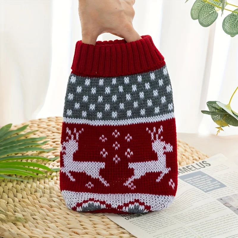 Le pull rouge à motif rennes, tenu à la main devant un fond clair