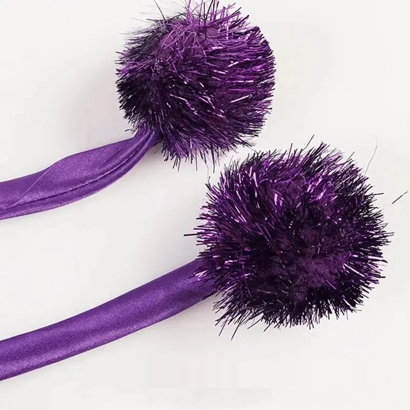 Les deux pompons violets et le cordon de serrage de la cape de sorcière